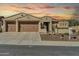 Inviting home featuring a 3-car garage, desert landscaping, and classic Southwestern architecture at sunset at 30696 N 130Th Ln, Peoria, AZ 85383