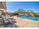 Resort-style backyard with a swimming pool, waterfall feature, lounge chairs, and an outdoor kitchen at 30696 N 130Th Ln, Peoria, AZ 85383
