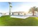 Backyard with modern white house, pool, green lawn, and palm trees on a sunny day at 7860 E Davenport Dr, Scottsdale, AZ 85260