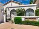 Charming home featuring a gated courtyard, lush greenery, arched windows, and a white facade, exuding curb appeal at 10120 E Topaz Dr, Scottsdale, AZ 85258