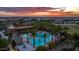 Aerial view of the community pool area with palm trees, lounge chairs, and a stunning sunset backdrop at 10129 E Ampere Ave, Mesa, AZ 85212