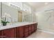 Bathroom featuring double sinks, frosted glass shower, and dark wood cabinets at 16331 W Willow Creek Ln, Surprise, AZ 85374