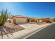 Tan house with a two-car garage and cacti in the front yard at 16331 W Willow Creek Ln, Surprise, AZ 85374