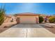 Two-car garage with a tan stucco exterior at 16331 W Willow Creek Ln, Surprise, AZ 85374