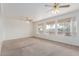 Bright living room with neutral carpet, three windows for natural light, and ceiling fans for comfort at 16331 W Willow Creek Ln, Surprise, AZ 85374