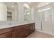 This bathroom boasts double sinks with dark wood cabinets and a tiled walk-in shower with a glass door at 18819 W Cholla St, Surprise, AZ 85388