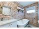 Spa-like bathroom featuring a clawfoot tub and exposed brick at 2111 W Mulberry Dr, Phoenix, AZ 85015