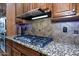 Gas cooktop with stainless steel range hood and granite countertop at 26293 W Sierra Pinta Dr, Buckeye, AZ 85396