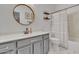 Gray vanity bathroom with a round mirror and striped shower curtain at 3020 E Lark Dr, Chandler, AZ 85286