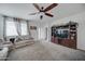 Cozy living room features neutral carpet, ceiling fan, and a built-in entertainment center at 30263 W Pinchot Ave, Buckeye, AZ 85396