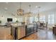 Bright kitchen features a granite-top island with a stainless steel sink and appliances, and modern light fixtures at 5344 E Catalina Ave, Mesa, AZ 85206