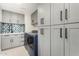 Contemporary laundry room with shaker cabinets, modern appliances, and stylish backsplash at 6809 E Gelding Dr, Scottsdale, AZ 85254