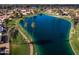 An aerial view of a serene lake surrounded by lush green spaces, walking paths, and residential homes at 9725 E Navajo Pl, Sun Lakes, AZ 85248