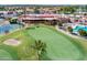 An aerial of the lush green golf course with trees and a building with a pool and tennis court at 9725 E Navajo Pl, Sun Lakes, AZ 85248