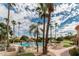 Community pool surrounded by lush landscaping, palm trees, lounge chairs and tables with umbrellas at 9725 E Navajo Pl, Sun Lakes, AZ 85248