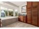 Bright bathroom with a large tub under a window and beautiful wood cabinets with a large mirror above a vanity at 211 E Dawn Dr, Tempe, AZ 85284