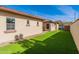 Backyard showing artificial turf, desert landscaping, and side of the house with windows at 2637 S Sandstone St, Gilbert, AZ 85295