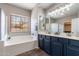 Well-lit bathroom with dual sinks, a large soaking tub, and a window with a view at 2637 S Sandstone St, Gilbert, AZ 85295