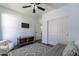 Light-filled bedroom with dark wood floors, a ceiling fan, a mounted television, and closet doors at 2637 S Sandstone St, Gilbert, AZ 85295