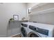 Bright laundry room featuring a modern washer and dryer and floating shelving for storage and decor at 2637 S Sandstone St, Gilbert, AZ 85295