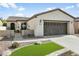 Tan stucco home with a two-car garage, landscaping, and walkway at 28107 N 123Rd Ln, Peoria, AZ 85383