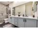 Modern bathroom with dual sinks, large mirror, and tiled shower with a glass door and shelves for storage at 3036 E Boston St, Gilbert, AZ 85295