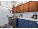 Laundry room with blue base cabinets, stainless steel washer and dryer and upper cabinets with storage baskets at 3036 E Boston St, Gilbert, AZ 85295