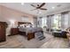 Main bedroom featuring a king bed with gray linens, an accent wall, and views of the outdoors through sheer curtains at 3036 E Boston St, Gilbert, AZ 85295