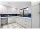 Bright kitchen featuring white cabinets, dark sink, blue tile backsplash, and patterned tile floors at 6331 E Earll Dr, Scottsdale, AZ 85251