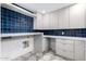 Well-organized laundry room featuring blue tiled backsplash, patterned tile floor, and ample counter space at 6331 E Earll Dr, Scottsdale, AZ 85251