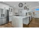 Bright kitchen with a large island, stainless steel fridge, white cabinetry, and modern pendant lighting at 7390 E Hanover Way, Scottsdale, AZ 85255