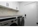 Laundry room features a modern washer and dryer with white cabinets and tiled backsplash at 7390 E Hanover Way, Scottsdale, AZ 85255