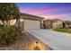 Picturesque front exterior featuring a wide driveway, mature landscaping, and charming architecture at dusk at 7815 W Cinder Brook Way, Florence, AZ 85132