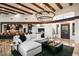 Bright living room featuring exposed wood beams, elegant chandelier, and open access to a modern kitchen at 10712 E Prospect Point Dr, Scottsdale, AZ 85262