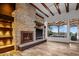 Living area featuring a stone fireplace, beamed ceiling, and wall of glass doors to covered patio at 10712 E Prospect Point Dr, Scottsdale, AZ 85262