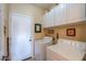 Functional laundry room with overhead storage cabinets and convenient access to the exterior at 1885 E Sycamore E Rd, Casa Grande, AZ 85122