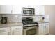 Close-up of stainless steel stove and microwave with white cabinets in bright kitchen at 3055 N Red Mtn # 156, Mesa, AZ 85207