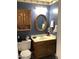 Powder room with wood vanity and oval mirror at 3554 E Camino Cir, Mesa, AZ 85213