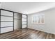 Bedroom with wood-look floors and open closet with sliding doors at 7714 E Mariposa Dr, Scottsdale, AZ 85251