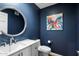 Stylish powder room with a round mirror, bright blue walls, and modern vanity at 9504 E Sunnyside Dr, Scottsdale, AZ 85260