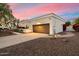 Exterior featuring a long driveway, a two-car garage, mature shade tree and desert landscaping at sunset at 9504 E Sunnyside Dr, Scottsdale, AZ 85260