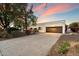 Home featuring a long driveway, a two-car garage, mature shade tree and desert landscaping at 9504 E Sunnyside Dr, Scottsdale, AZ 85260