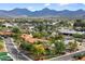 Scenic view of a residential neighborhood with lush landscaping, mature trees, and mountain views in the distance at 9504 E Sunnyside Dr, Scottsdale, AZ 85260