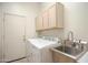 Laundry room featuring cabinets, sink, and modern appliances at 12743 W Highland Ave, Litchfield Park, AZ 85340