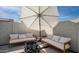 Comfortable patio seating area with plush sofas, a modern firepit and shade umbrella at 1723 W Brianna Rd, Phoenix, AZ 85085