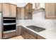 Close-up of kitchen boasts built-in oven, gas range, stainless vent, white backsplash, and quartz countertop at 18180 E Tiffany Dr, Queen Creek, AZ 85142