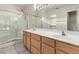 Bathroom featuring a double sink vanity with a mirror, tiled flooring, and a glass door shower at 19850 N 110Th Ln, Peoria, AZ 85373