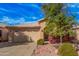 Exterior of beige single-story home featuring a two-car garage and desert landscaping at 19850 N 110Th Ln, Peoria, AZ 85373