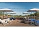 Outdoor seating area with umbrellas and tables near a basketball court at 26021 N 23Rd Ave, Phoenix, AZ 85085