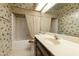 Bathroom with wallpaper has a beige sink, mirror, and toilet next to a tub with a shower curtain at 26622 S Beech Creek Dr, Sun Lakes, AZ 85248